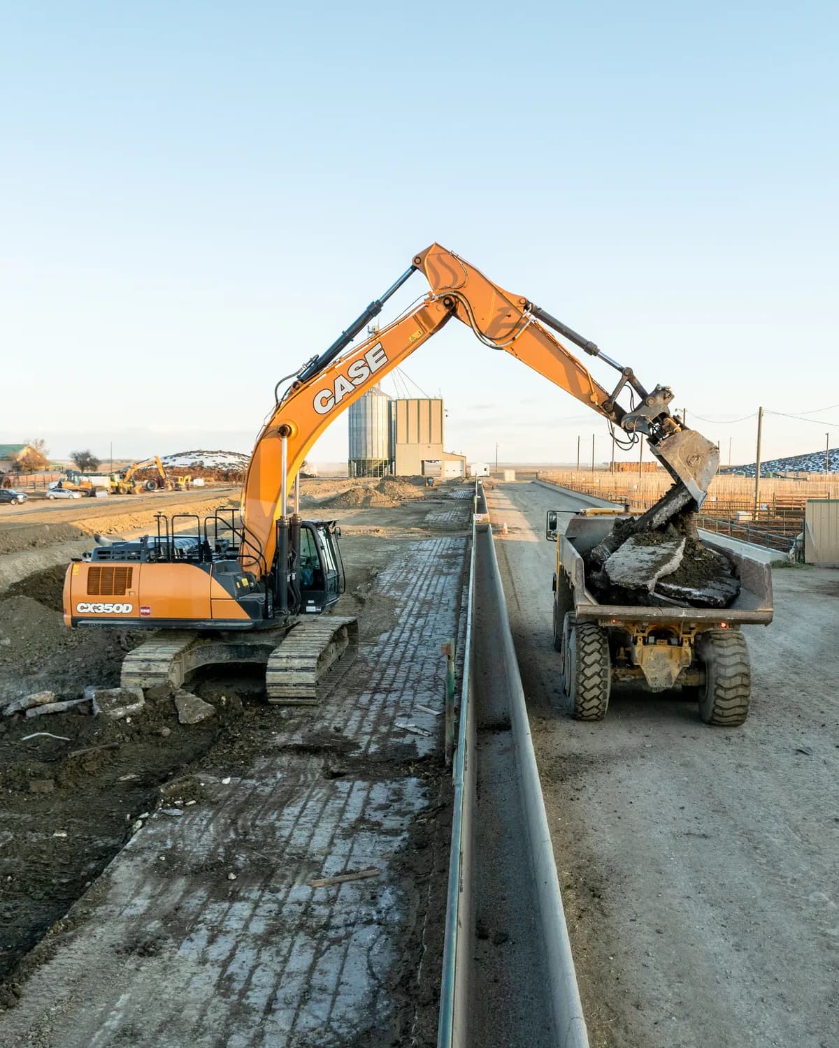 Subterrain demolition excavator loading broken concrete into an articulated dump truck at an Alberta worksite