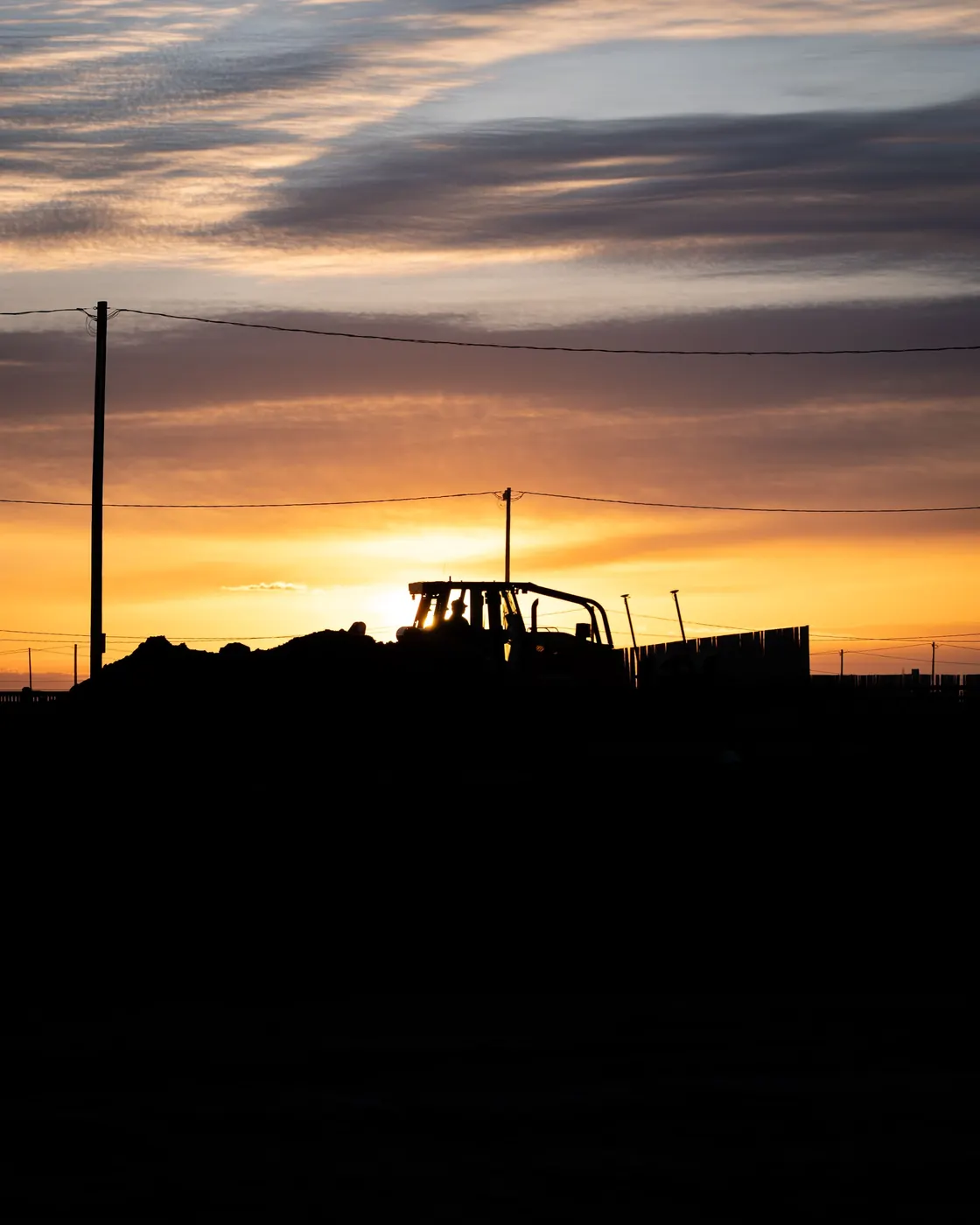 Heavy equipment silhouetted against an Alberta sunset