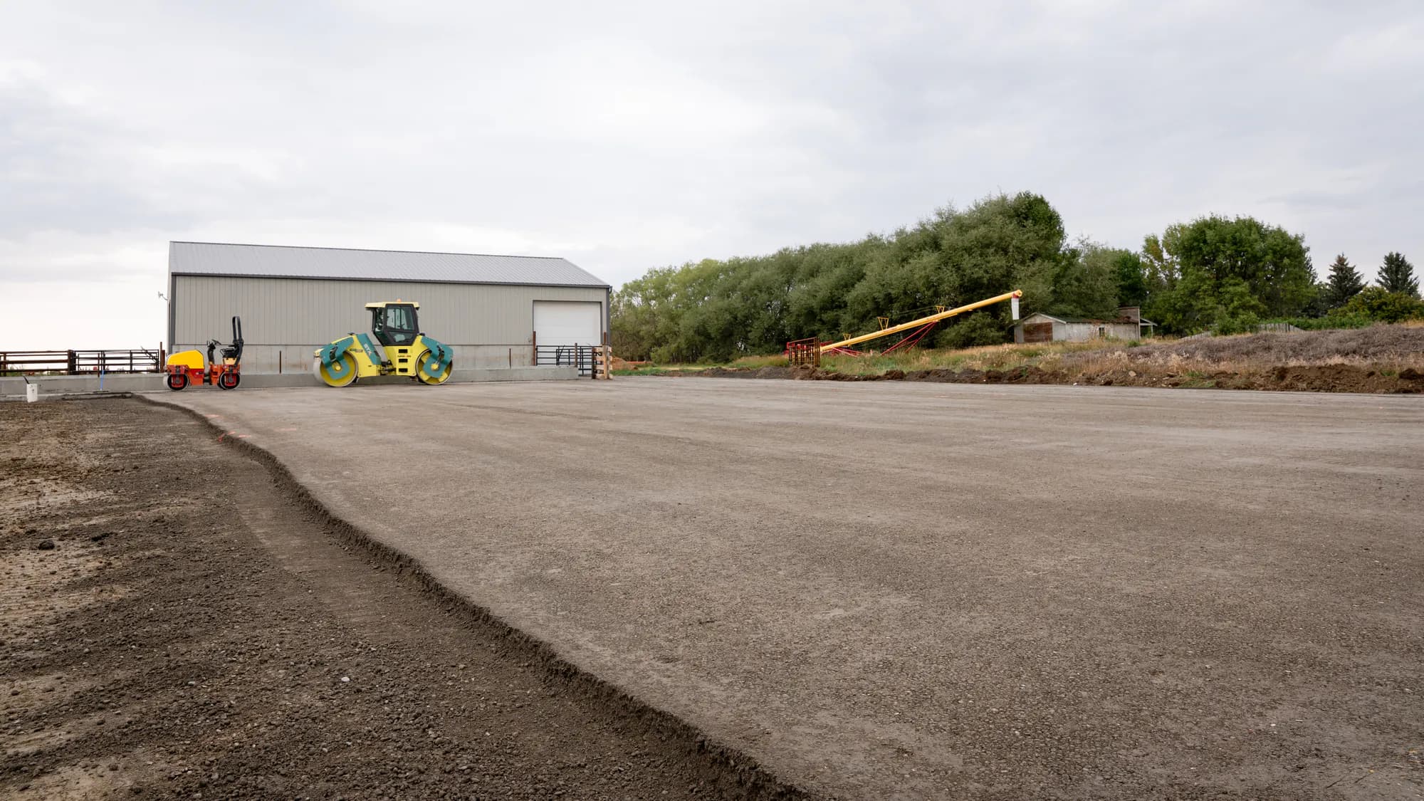Rollers compacting a roller compacted concrete feedlot surface in Alberta